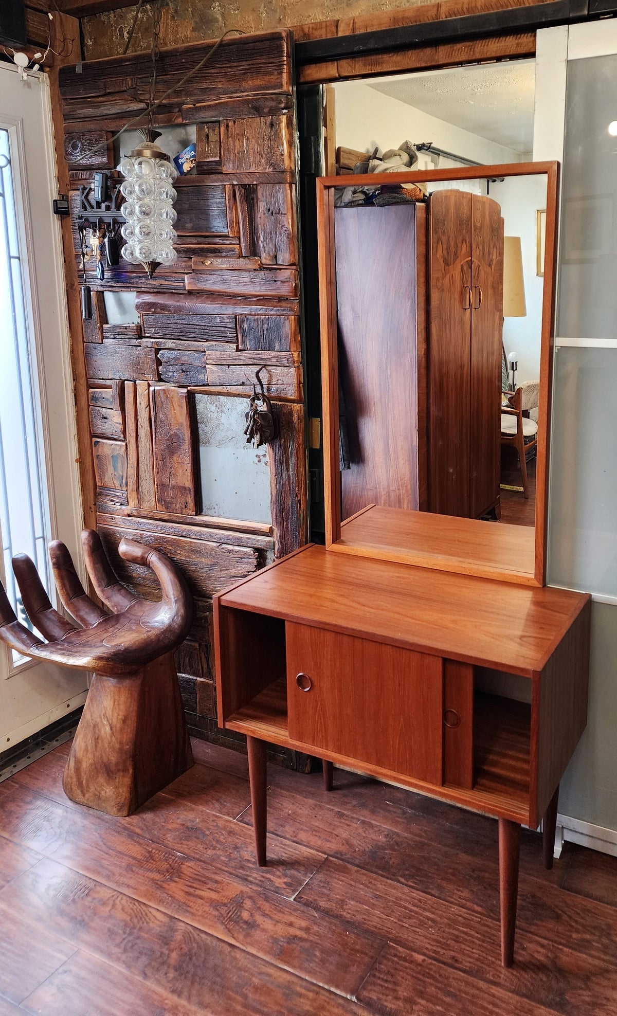 A teak cabinet with two sliding doors and a mirror, refinished in a Danish oil finish, displayed in a room with an open door policy.