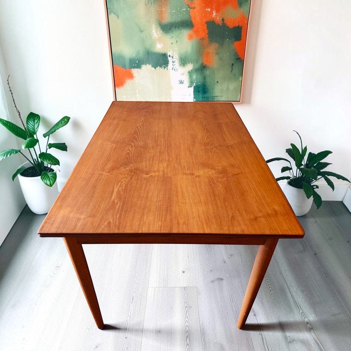 Mid Century Modern Toronto refinished Danish teak and oak extendable dining table with tapered legs in a bright room.